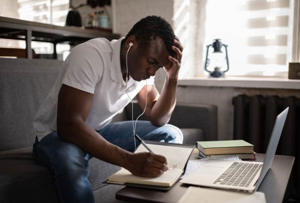 Professional job seeker taking notes beside a laptop