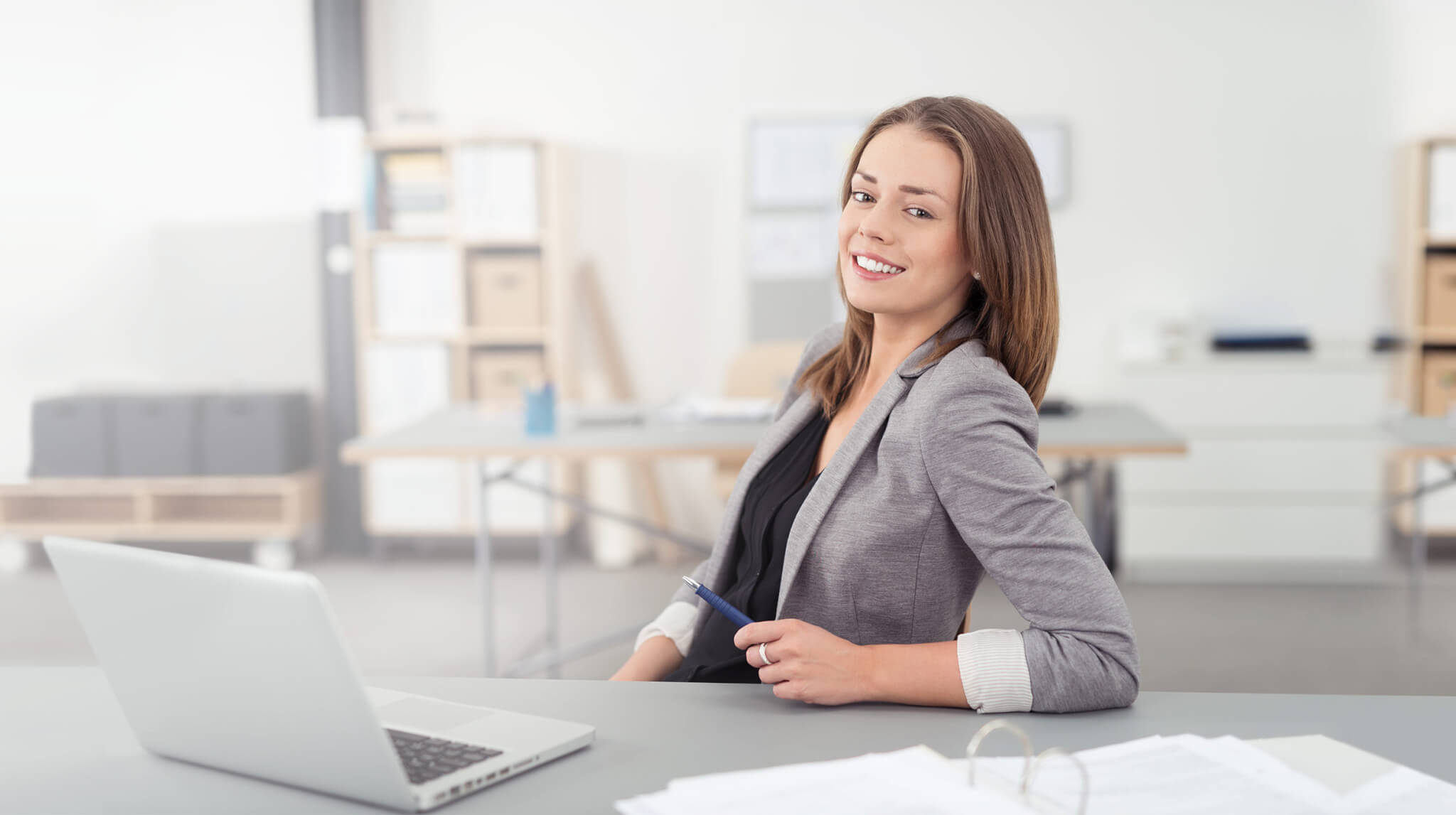 Professional woman smiling at a desk with a laptop